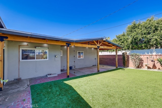 exterior space featuring a patio area, fence, a lawn, and stucco siding