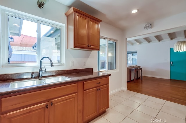 kitchen featuring light tile patterned floors, dark countertops, recessed lighting, brown cabinetry, and a sink