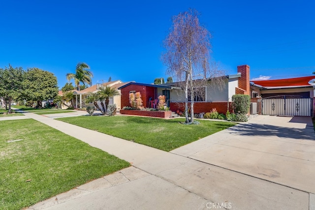 view of front of house with brick siding, a gate, concrete driveway, and a front yard