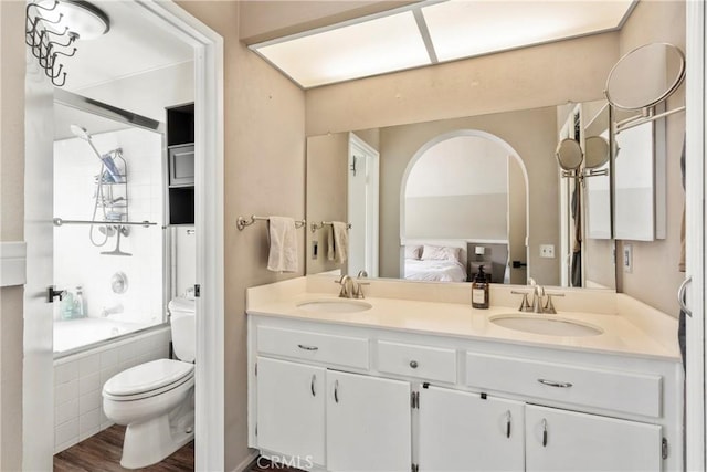 ensuite bathroom with tiled shower / bath, double vanity, a sink, and toilet