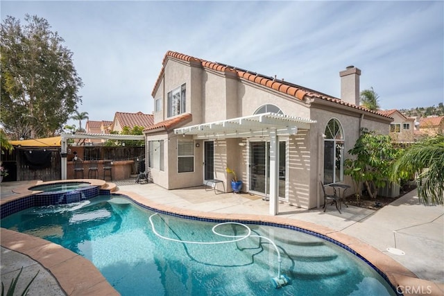 back of property with a patio, a chimney, a pool with connected hot tub, a pergola, and stucco siding