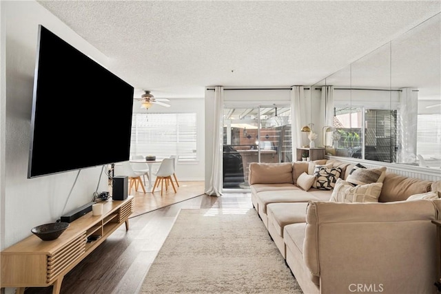 living area featuring a textured ceiling, wood finished floors, and a ceiling fan