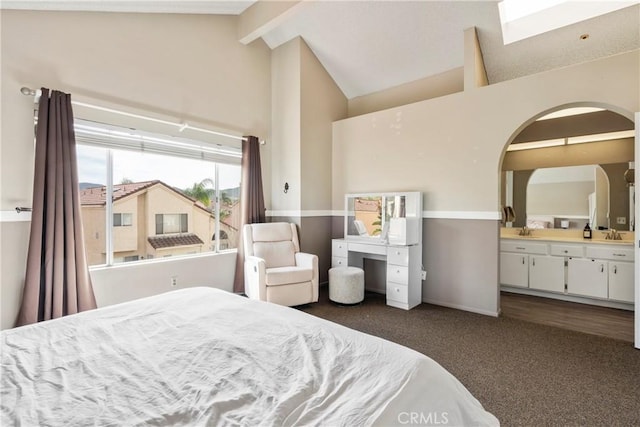 bedroom featuring beam ceiling, dark colored carpet, connected bathroom, a sink, and high vaulted ceiling