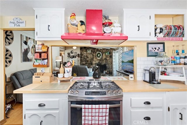 kitchen with light wood finished floors, light countertops, backsplash, white cabinetry, and stainless steel gas range