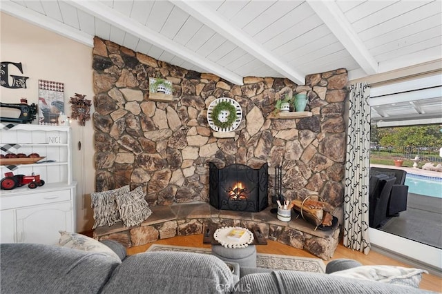 living area featuring a fireplace, lofted ceiling with beams, and wood finished floors