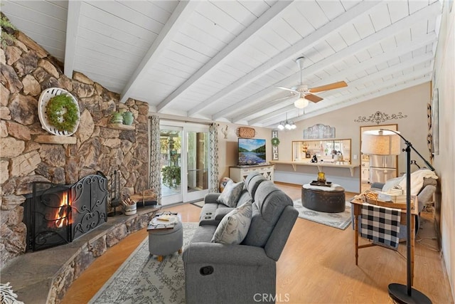 living area featuring lofted ceiling with beams, wood ceiling, ceiling fan, wood finished floors, and a stone fireplace