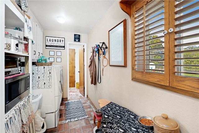 interior space with stainless steel microwave, brick floor, and washing machine and dryer