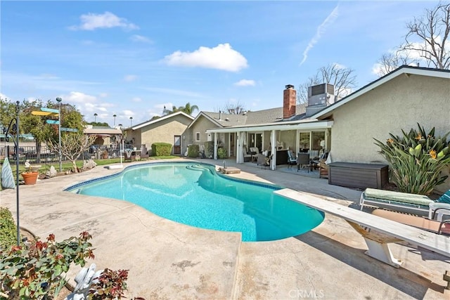 view of pool featuring a patio area, fence, a diving board, and a fenced in pool