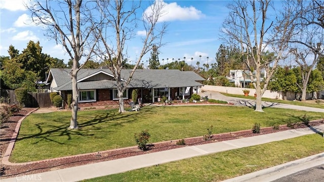 ranch-style house with brick siding, a front yard, and fence