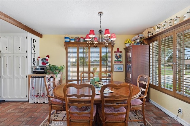 dining room with brick floor, a notable chandelier, a textured ceiling, and baseboards