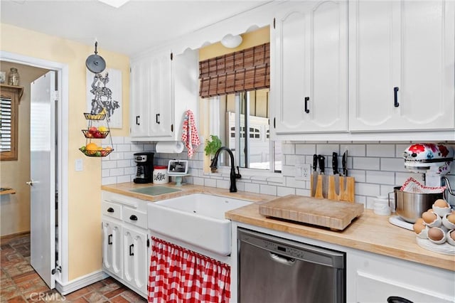 kitchen with tasteful backsplash, white cabinetry, a sink, dishwasher, and baseboards