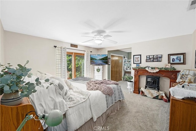 bedroom with a ceiling fan, a glass covered fireplace, light colored carpet, and visible vents