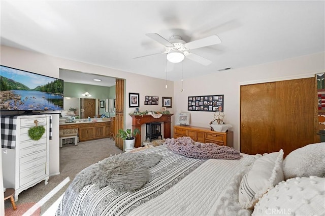 carpeted bedroom featuring a fireplace, a closet, visible vents, ceiling fan, and ensuite bath