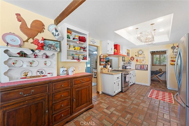 kitchen featuring a chandelier, brick floor, light countertops, appliances with stainless steel finishes, and a raised ceiling