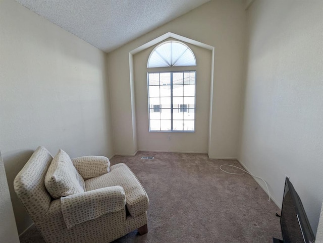 sitting room featuring lofted ceiling, a textured ceiling, visible vents, and carpet flooring