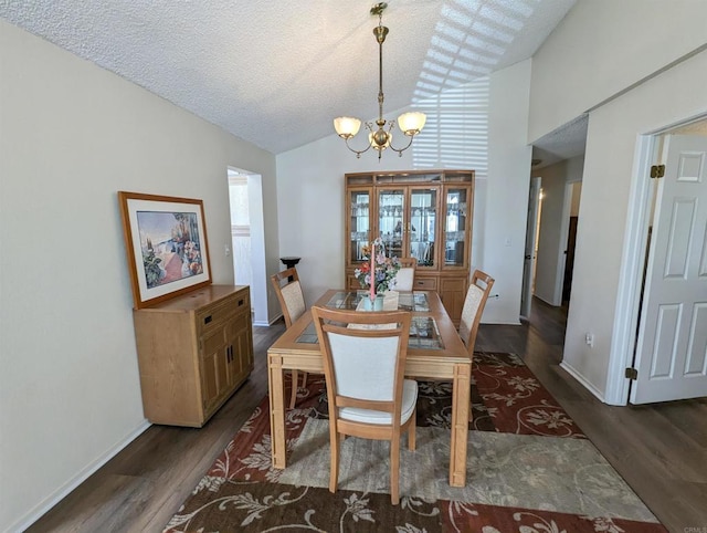 dining room with a textured ceiling, a chandelier, vaulted ceiling, and dark wood finished floors