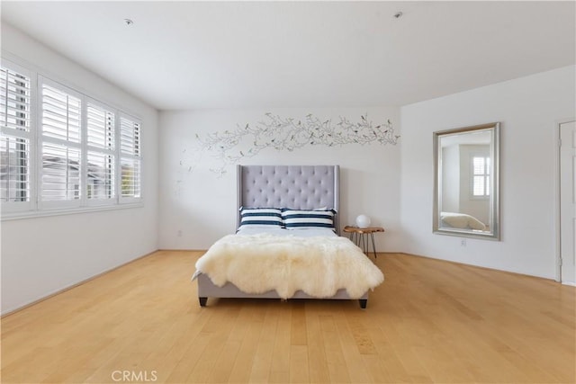 bedroom with multiple windows and wood finished floors