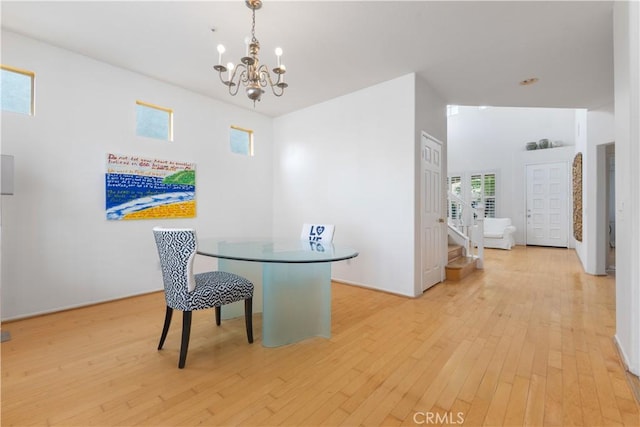 dining space featuring a chandelier, light wood-type flooring, and stairs