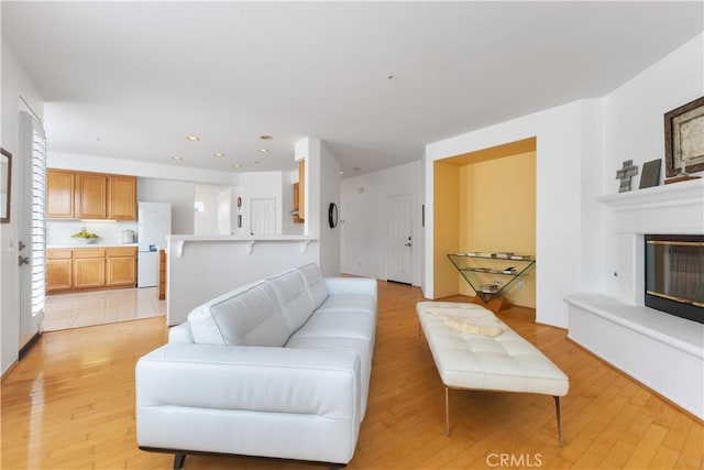 living room with light wood-type flooring, a glass covered fireplace, and recessed lighting