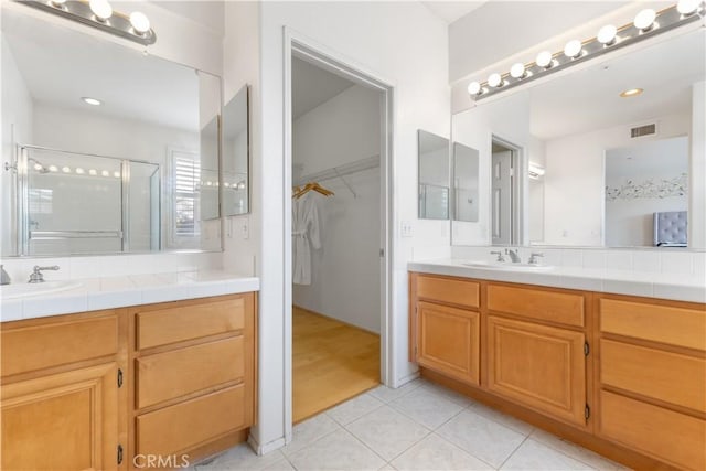 bathroom with tile patterned flooring, vanity, visible vents, a stall shower, and a walk in closet