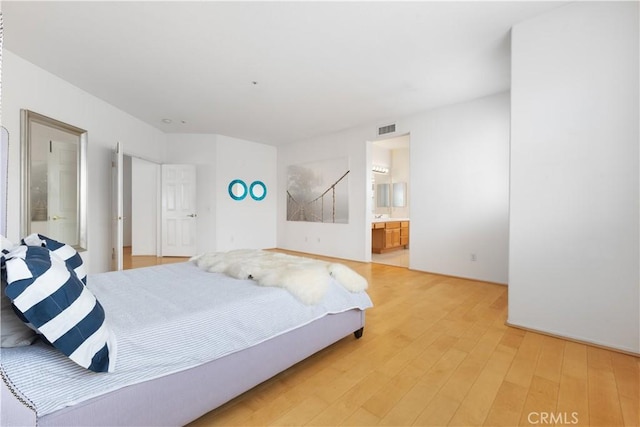 bedroom with ensuite bathroom, light wood-type flooring, and visible vents