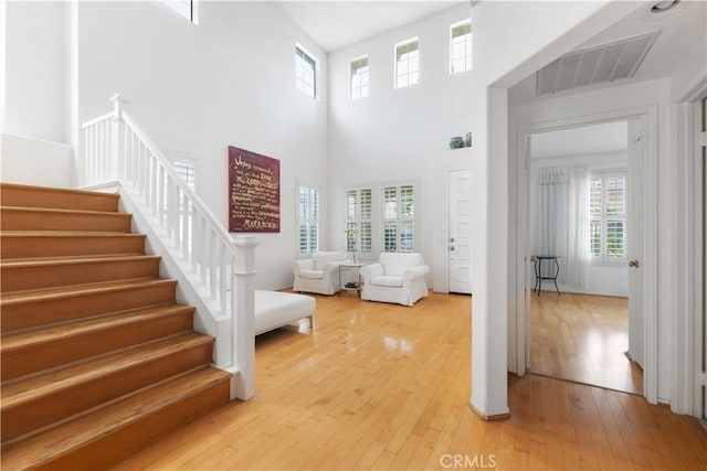 foyer featuring visible vents, stairway, a high ceiling, and hardwood / wood-style flooring