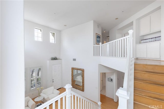 staircase featuring visible vents, a high ceiling, and wood finished floors