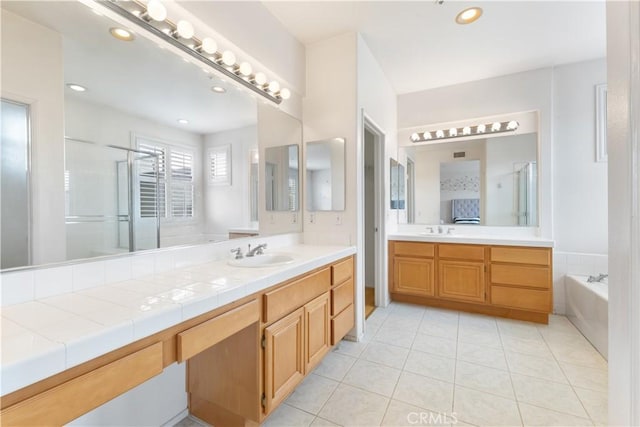 bathroom with a stall shower, a garden tub, tile patterned flooring, vanity, and recessed lighting