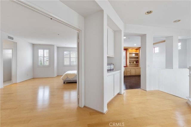 hall featuring light wood-type flooring, visible vents, and recessed lighting