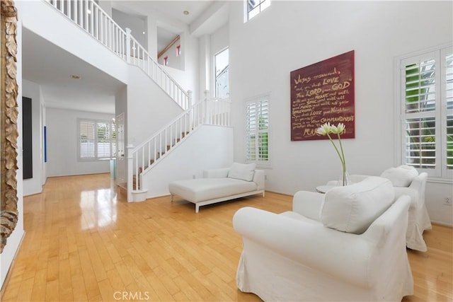 living room featuring stairs, a high ceiling, and wood finished floors