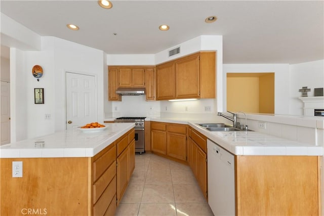 kitchen featuring light countertops, high end stove, white dishwasher, and a sink