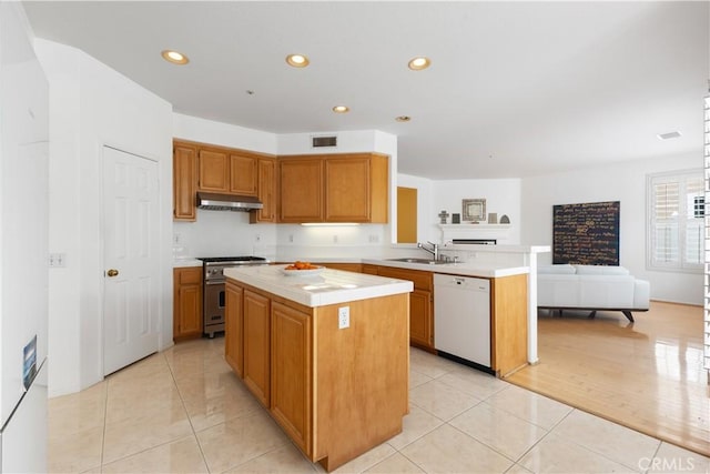 kitchen featuring visible vents, white dishwasher, high end stove, under cabinet range hood, and a sink