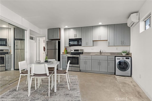 kitchen featuring washer / dryer, a wall unit AC, stainless steel appliances, gray cabinetry, and a sink