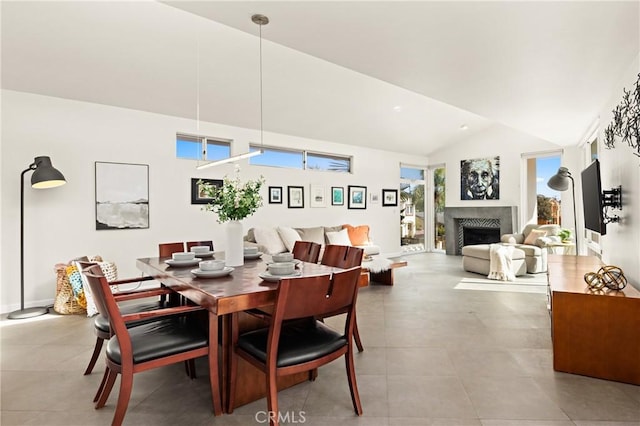 tiled dining room featuring high vaulted ceiling, plenty of natural light, and a fireplace