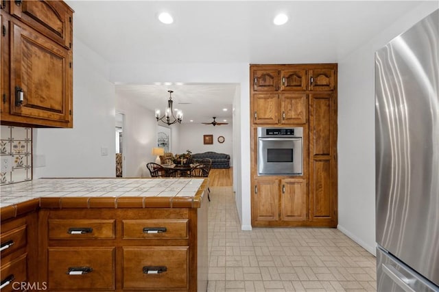 kitchen featuring stainless steel appliances, brown cabinetry, a peninsula, and recessed lighting