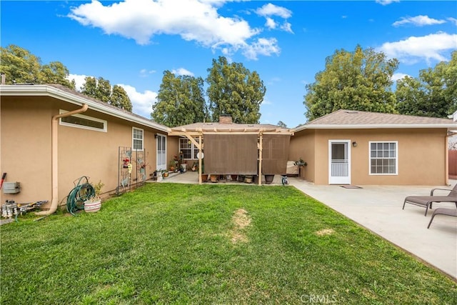 back of house featuring a lawn, a patio area, and stucco siding