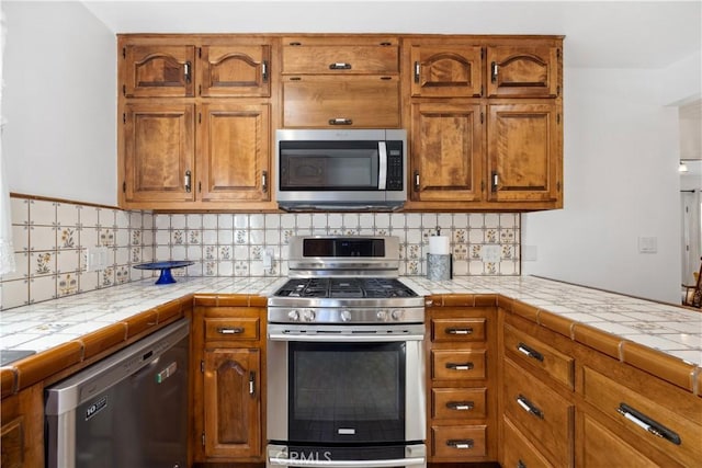 kitchen with stainless steel appliances, brown cabinets, and backsplash