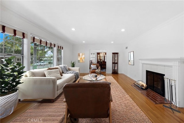 living room with light wood-type flooring, a brick fireplace, and ornamental molding