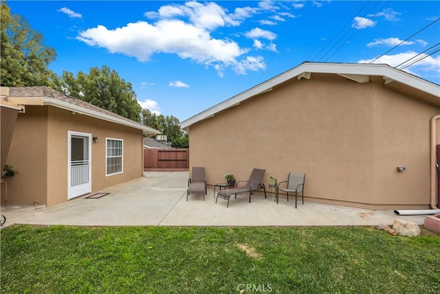 back of property featuring a patio area, fence, a lawn, and stucco siding