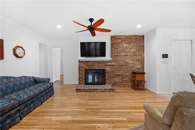 living room with a brick fireplace, a ceiling fan, wood finished floors, and recessed lighting