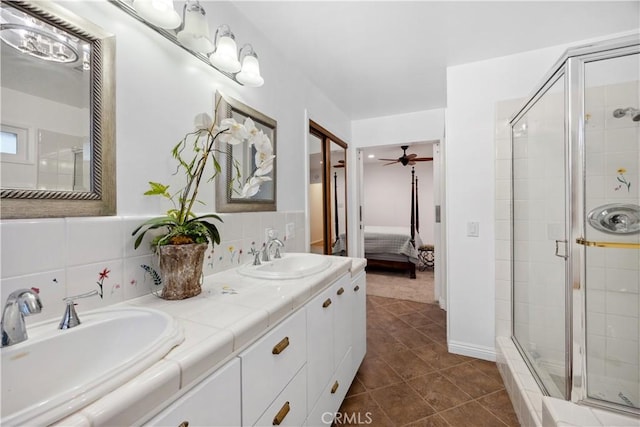 bathroom featuring decorative backsplash, a sink, a shower stall, and ensuite bath