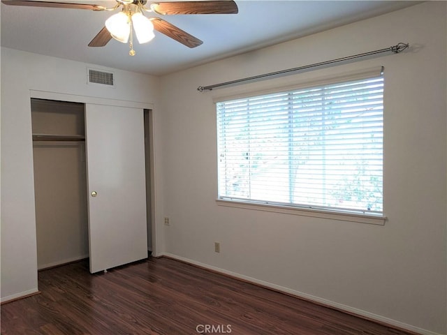 unfurnished bedroom with a closet, visible vents, a ceiling fan, wood finished floors, and baseboards