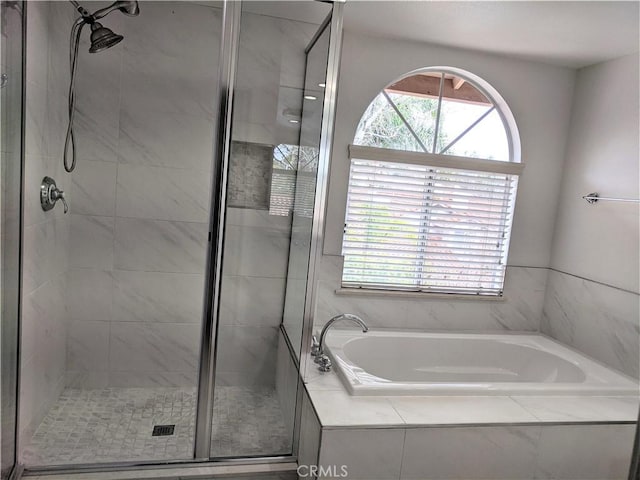 bathroom featuring a shower stall and a bath