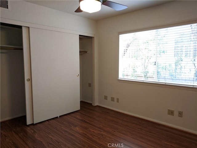 unfurnished bedroom with baseboards, ceiling fan, visible vents, and dark wood-type flooring