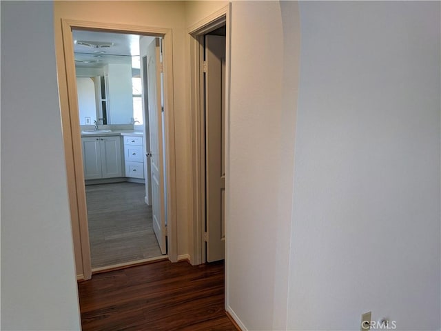 hall with baseboards, dark wood-style flooring, and a sink