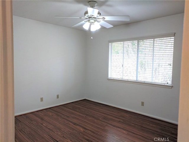 spare room featuring ceiling fan, dark wood finished floors, and baseboards