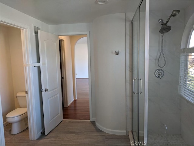 bathroom with a stall shower, visible vents, toilet, and wood finished floors