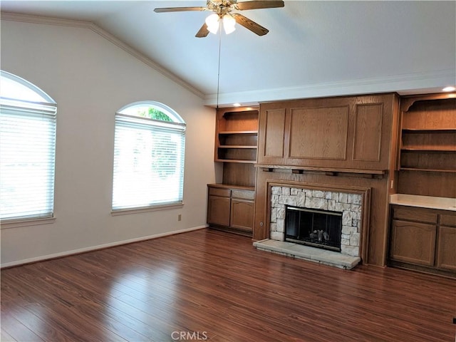 unfurnished living room featuring a stone fireplace, dark wood-style flooring, a ceiling fan, vaulted ceiling, and ornamental molding