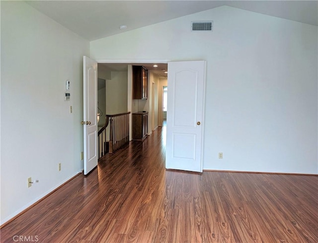 empty room with lofted ceiling, baseboards, visible vents, and wood finished floors