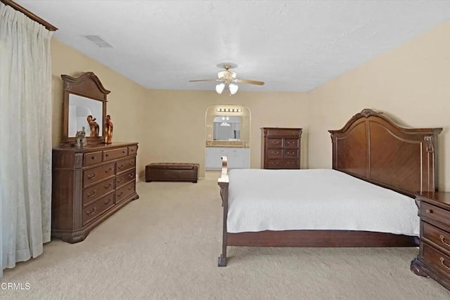 carpeted bedroom featuring arched walkways, visible vents, ceiling fan, and ensuite bath